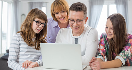 Smiling group of 4 family in front of the laptop